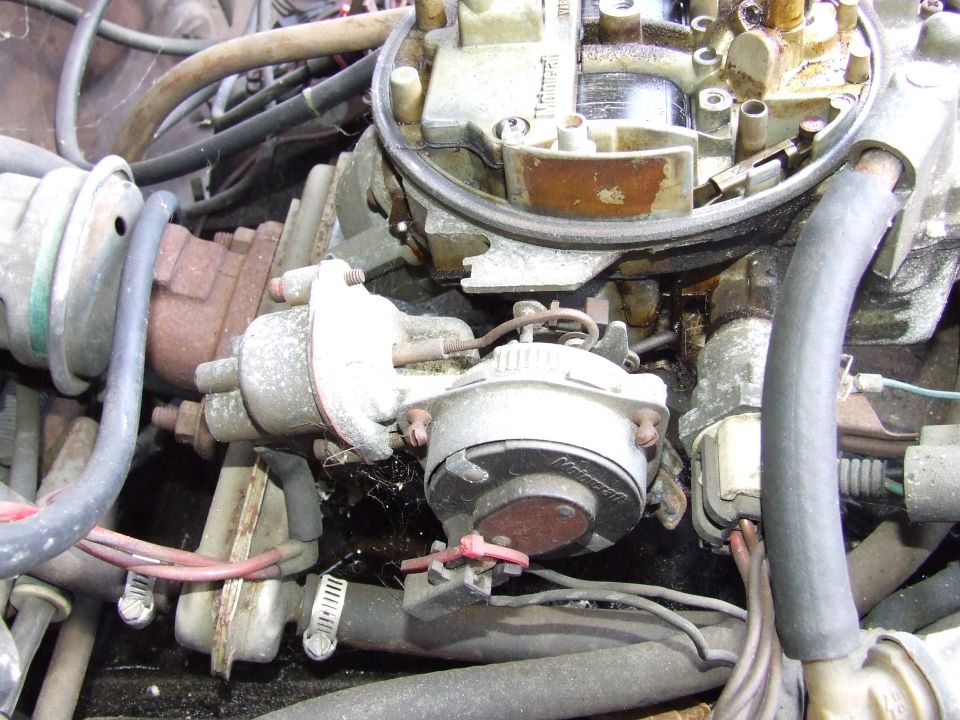 Close-up of a carburetor with hoses and wiring attached