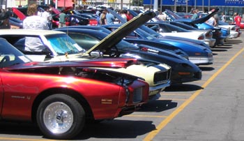 1991 Ford Bronco - A line of cars with their hoods open, parked in an outdoor lot.
