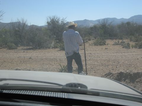 1986 Ford Bronco - A man stands in a dry, rural landscape, holding a pole and looking out at the scenery.