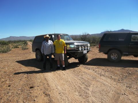 1986 Ford Bronco - Two men stand beside a black Ford Bronco on a dusty road with another Bronco in the background.