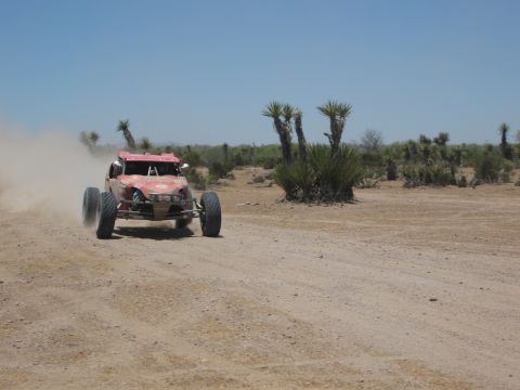 1986 Ford Bronco - A desert buggy races across a dusty, arid terrain under a clear blue sky.