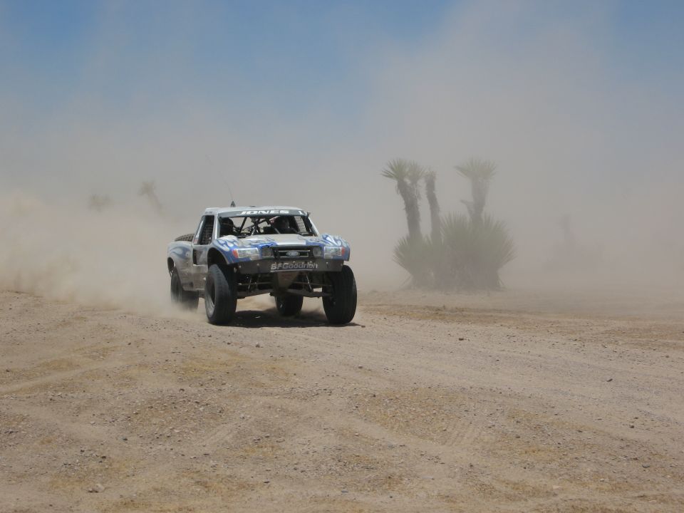 Off-road race truck kicking up dust on a dirt track