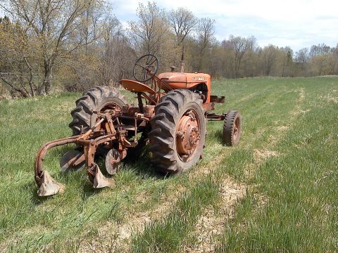 2000 Chevrolet Tahoe - This vintage tractor, equipped with a plow, sits in a field under a partly cloudy sky.