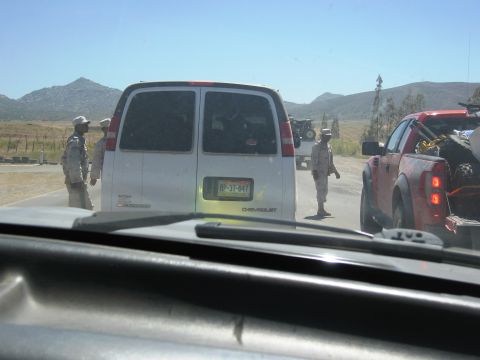 1986 Ford Bronco - Two vehicles, a van and a pickup truck, are stopped on a road with people in uniform nearby.
