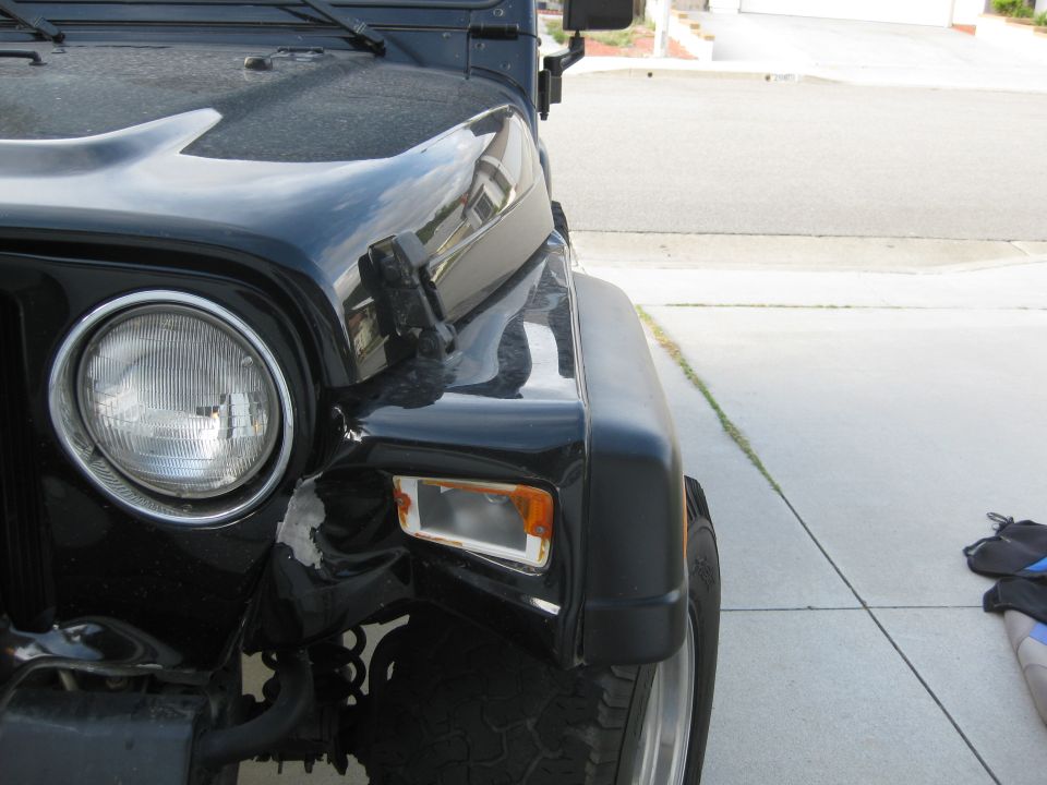 Black Jeep Wrangler front fender and headlight with damage