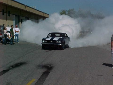 1991 Ford Bronco - A black muscle car performs a burnout, creating a large cloud of smoke.