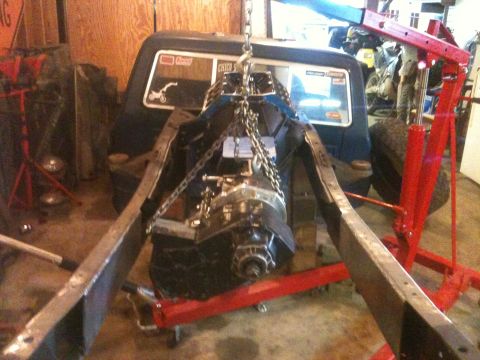 1976 Ford F-100 - Engine and transmission assembly is lowered into the frame of a 1976 Ford F-100 during a build.