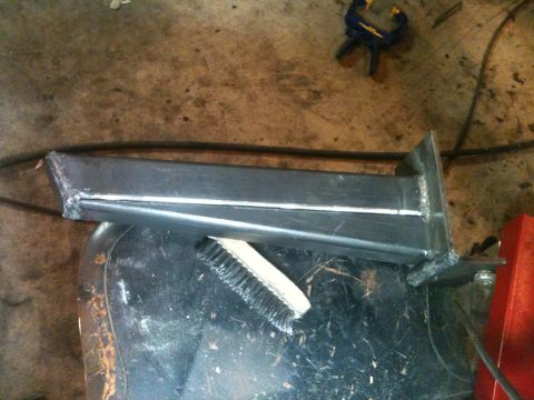 1976 Ford F-100 - A custom metal part, likely for a vehicle build, is shown with a brush resting on it. The Supermotors.net logo is in the corner.