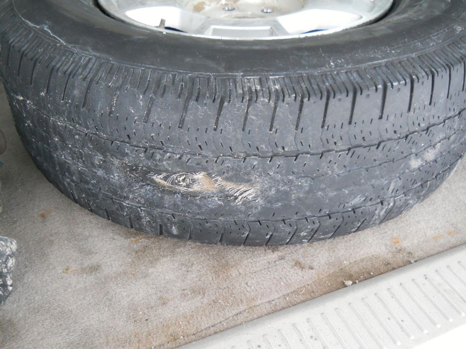Tire with a large gash on the sidewall. Rim is visible
