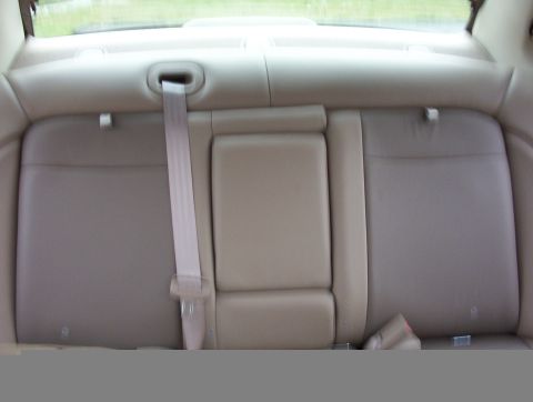 2003 Ford Taurus - Slightly blurred interior shot of a sedan's tan leather rear bench seat with the center armrest folded down and the shoulder belt draped ac…