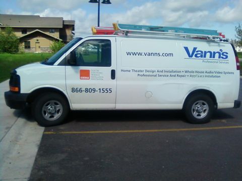 2006 Ford E350 - White cargo van parked in a lot, equipped with ladders on the roof rack.