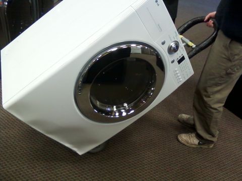 2006 Ford E350 - A person is moving a white LG washing machine on a dolly across a carpeted floor.