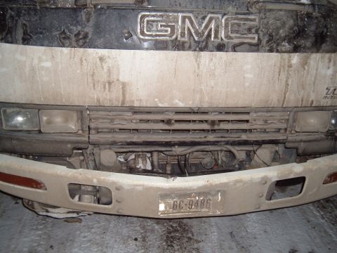 2006 Ford E350 - Front view of a GMC truck, covered in dirt, with a visible license plate.