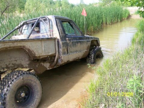 1987 Jeep Comanche - This 1987 Jeep Comanche is navigating a muddy water obstacle, equipped for off-road adventures.
