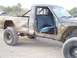 1987 Jeep Comanche - A lifted pickup truck is parked outdoors with its doors open, revealing the interior.