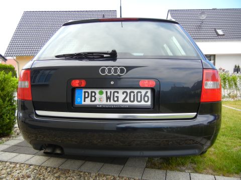 2003 Audi A6 - The rear of a black Audi wagon is shown parked in a driveway with a house and lawn in the background.