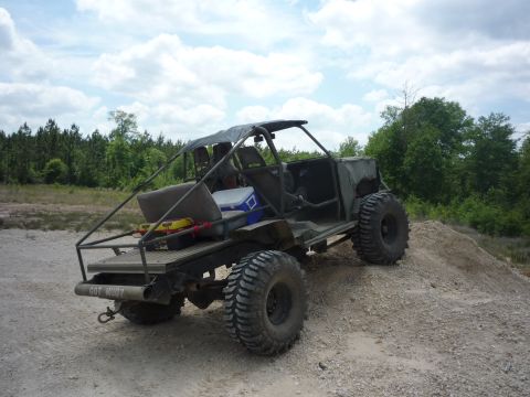 1990 Ford Bronco - This custom off-road vehicle features large tires and an open-air design, seen from a three-quarter rear angle.