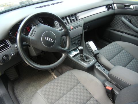 2003 Audi A6 - Interior view of an Audi showing checkered fabric seats, a manual shifter, and the steering wheel with the Audi logo.