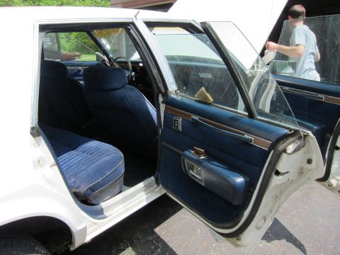 1991 Ford LTD Crown Victoria - View of the interior of a white sedan, showing the blue upholstered seats and door panels with the driver's side doors ajar.