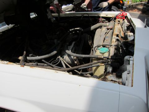 1991 Ford LTD Crown Victoria - The engine bay of a white car shows the radiator and various engine parts, with signs of rust.