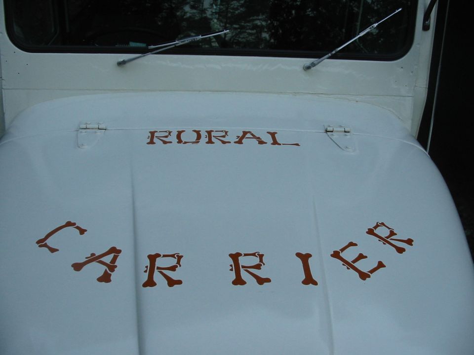 White Jeep hood with brown text 'RURAL CARRIER', windshield wipers visible