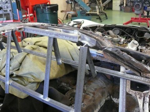 1976 Chevrolet Corvette - The vehicle's frame and engine compartment are exposed during a repair process in a workshop setting.