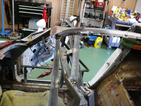 1976 Chevrolet Corvette - Car body shell in disrepair, with visible rust and structural supports in a workshop setting.