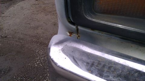 1984 Ford Bronco - The front corner of a vehicle shows a dented bumper and rust near the headlight assembly.