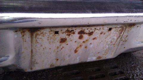 1984 Ford Bronco - Close-up of a heavily rusted rear bumper, showing signs of wear and age.