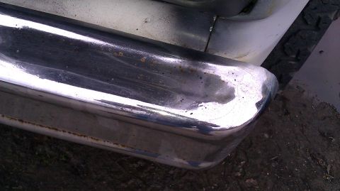 1984 Ford Bronco - Close-up of a chrome bumper corner, showing signs of wear and tear.