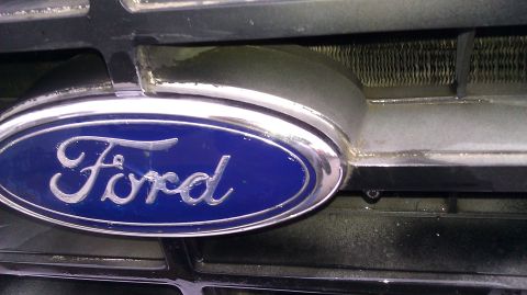 1984 Ford Bronco - Close-up of a Ford emblem on the front grille of a vehicle.