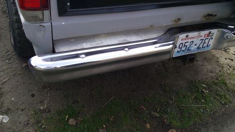 1984 Ford Bronco - Close-up of a vehicle's rear bumper, showing a Washington state license plate and a trailer hitch receiver.