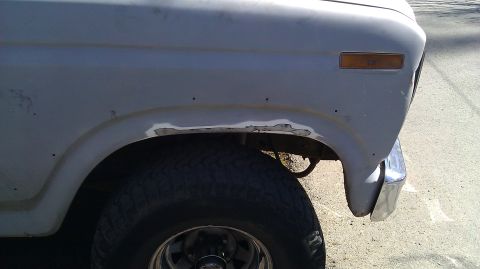 1984 Ford Bronco - Close-up of fender rust repair on a 1984 Ford Bronco, showing primer and bodywork.