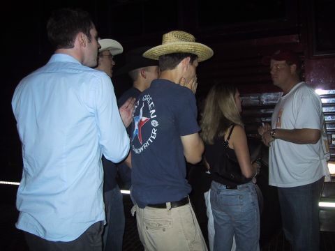 1989 Ford Bronco - People gather in a dimly lit indoor space, with some wearing hats and casual clothing.