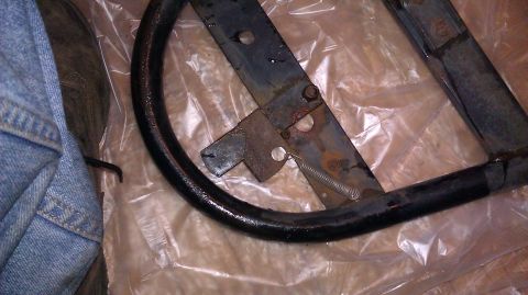 1984 Ford Bronco - This is a close-up view of a spare tire mount bracket, showing its metal construction and signs of rust.