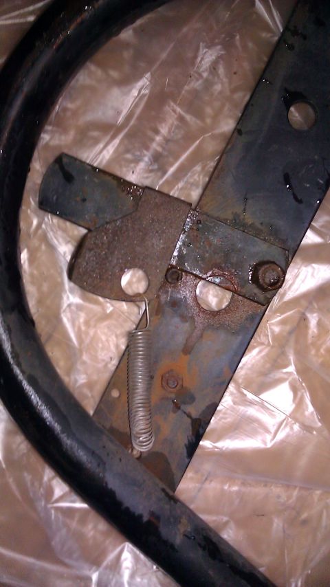 1984 Ford Bronco - Spare tire rack mechanism showing rust and a coiled spring.