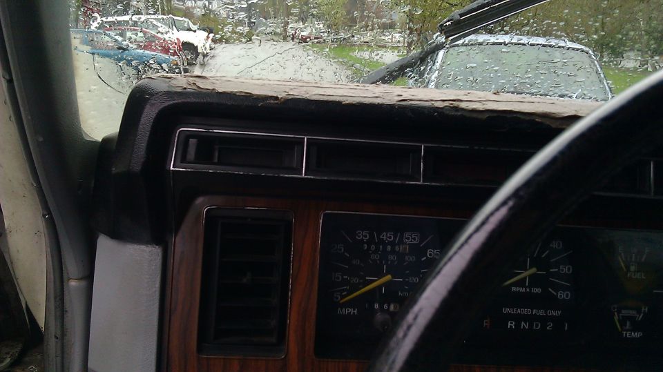 Dashboard of a 1984 Ford Bronco with wood grain trim and a cracked dash pad