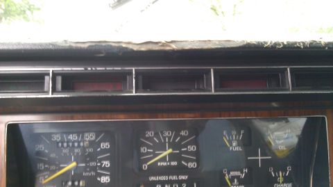 1984 Ford Bronco - Interior view of a 1984 Ford Bronco's dashboard, analog gauges for speed, RPM, fuel, and oil, along with wood grain accents.