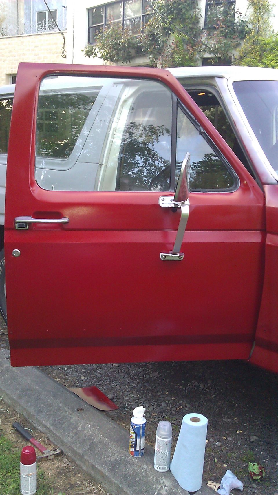 red truck door open, showing interior and another vehicle reflected in window