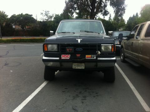 1990 Ford Bronco - Front view of a 1990 Ford Bronco parked in a lot, showing its bull hood ornament and grille guard.