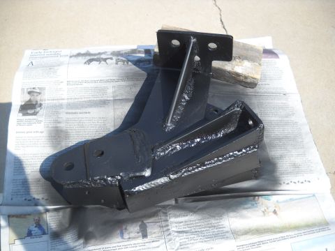 1986 Ford Bronco II - A black metal bracket is shown on top of newspaper pages, with a wooden block supporting one end.