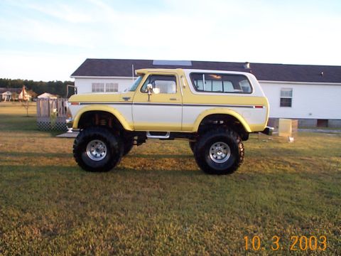 1978 Ford Bronco - This lifted Ford Bronco sits on a grassy lawn with a house in the background under a clear sky.