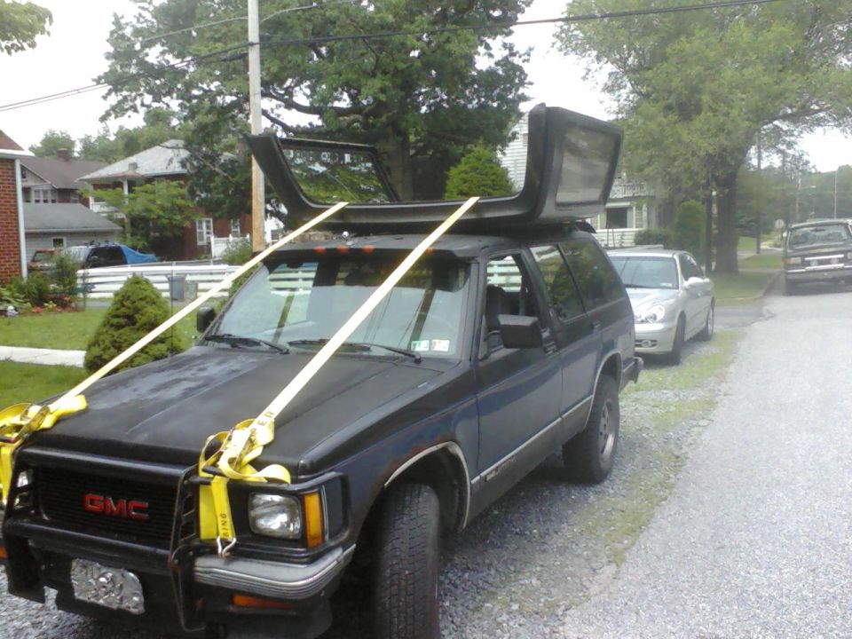 Dark blue GMC SUV with roof removed and strapped to roof rack