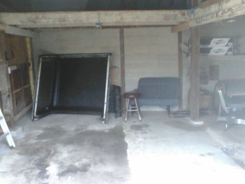 1988 Ford Bronco - A truck cap is stored in a garage next to a stool and a bench.