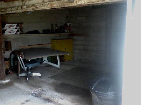 1988 Ford Bronco - A car's roof and door section has been repurposed as a desk in a garage setting.