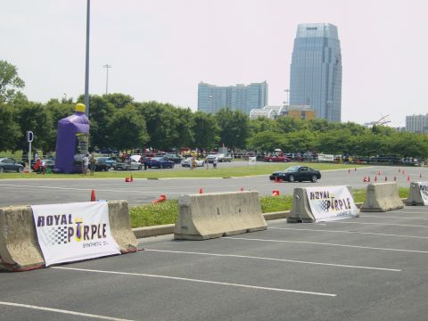 2007 Ford Mustang - Cars gathered in a parking lot with event banners and city skyline in the distance.