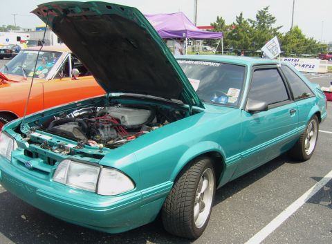 2007 Ford Mustang - A teal Ford Mustang from the late 1980s is displayed with its hood up at an outdoor event.