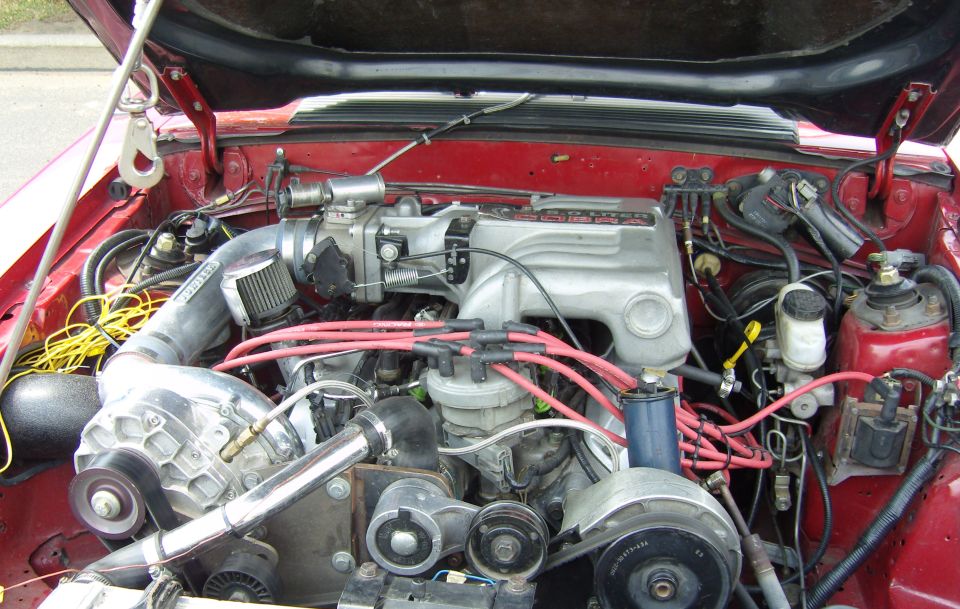 Engine bay showing a supercharger, intake manifold, distributor, and wiring