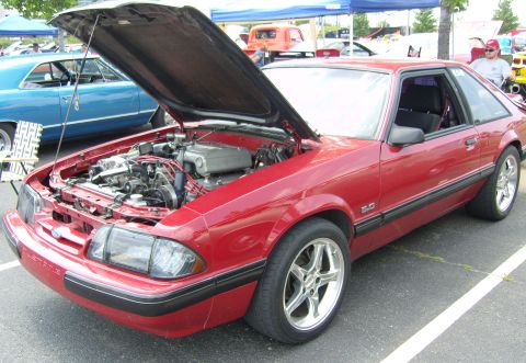 2007 Ford Mustang - A red Ford Mustang, likely from the late 1980s, is parked with its hood open, revealing the engine bay.