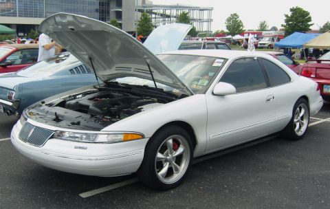 2007 Ford Mustang - A white Lincoln Mark VIII is displayed with its hood open, parked beside a classic blue car at an outdoor event.